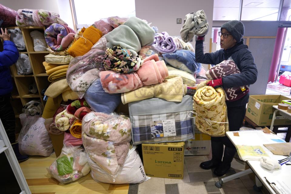 People bring extra blankets for evacuees at an evacuation center in Wajima in the Noto peninsula facing the Sea of Japan, northwest of Tokyo, Sunday, Jan. 7, 2024. Monday's temblor decimated houses, twisted and scarred roads and scattered boats like toys in the waters, and prompted tsunami warnings. (AP Photo/Hiro Komae)