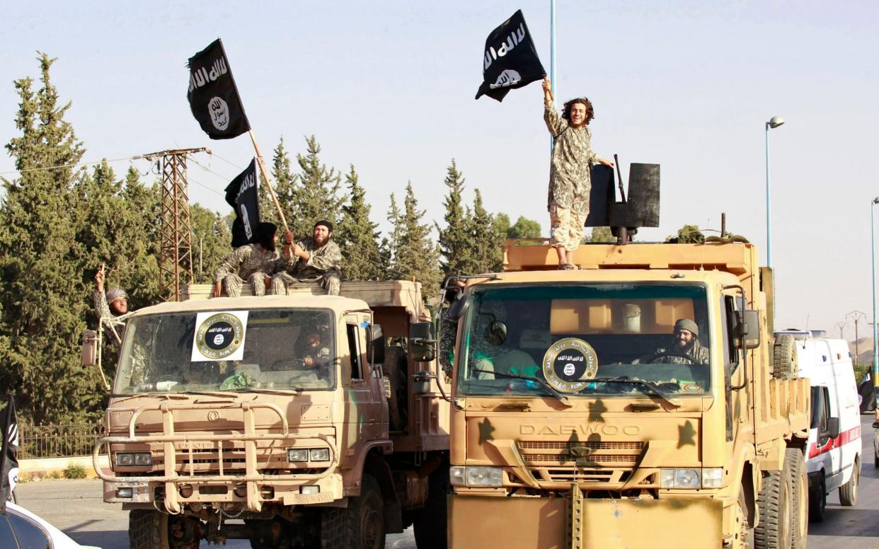 Militant Islamist fighters wave flags as they take part in a military parade along the streets of Raqqa - Reuters