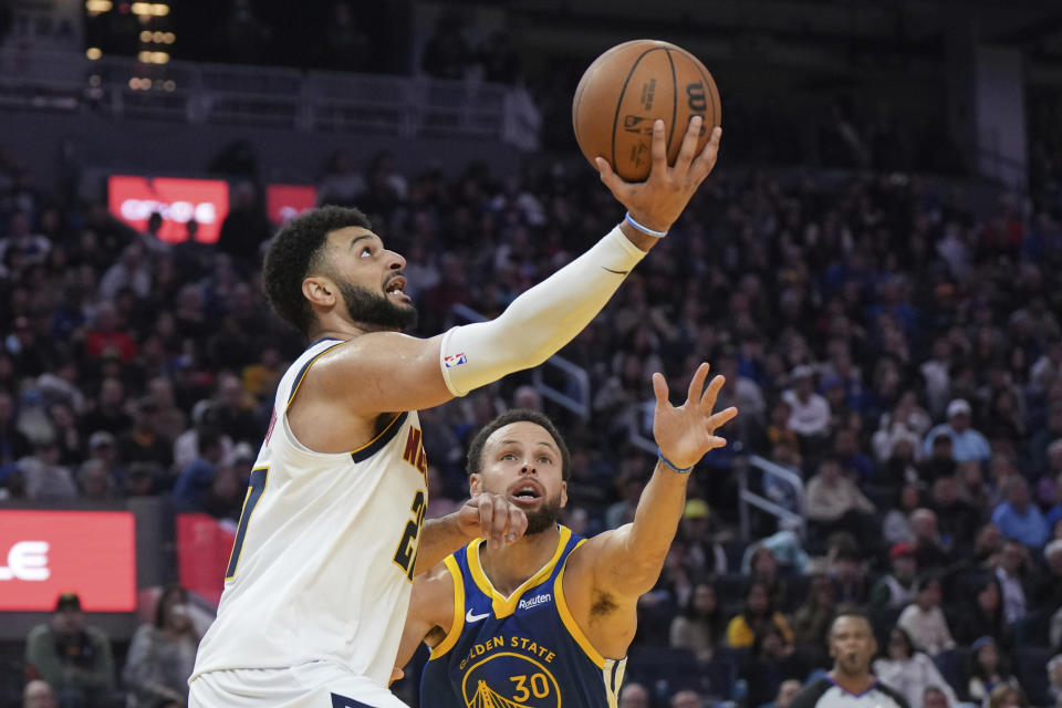 Denver Nuggets guard Jamal Murray (27) drives to the basket as Golden State Warriors guard Stephen Curry (30) defends during the first half of an NBA basketball game Thursday, Jan. 4, 2024, in San Francisco. (AP Photo/Loren Elliott)