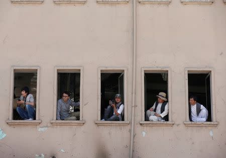 Men watch demonstrators from Afghanistan's Hazara minority during a protest in Kabul, Afghanistan July 23, 2016. REUTERS/Omar Sobhani