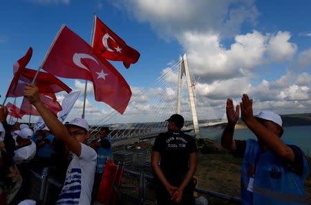 People wave Turkish flags during the opening ceremony of newly built Yavuz Sultan Selim bridge, the third bridge over the Bosphorus linking the city's European and Asian sides, in Istanbul, Turkey, August 26, 2016. REUTERS/Murad Sezer