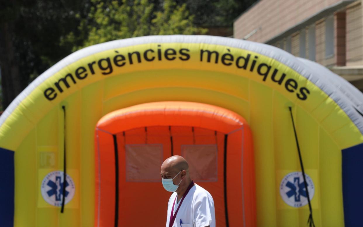 A health worker wearing a protective mask walks past a field hospital to control the coronavirus outbreak in Lleida, Spain - REUTERS/Nacho Doce