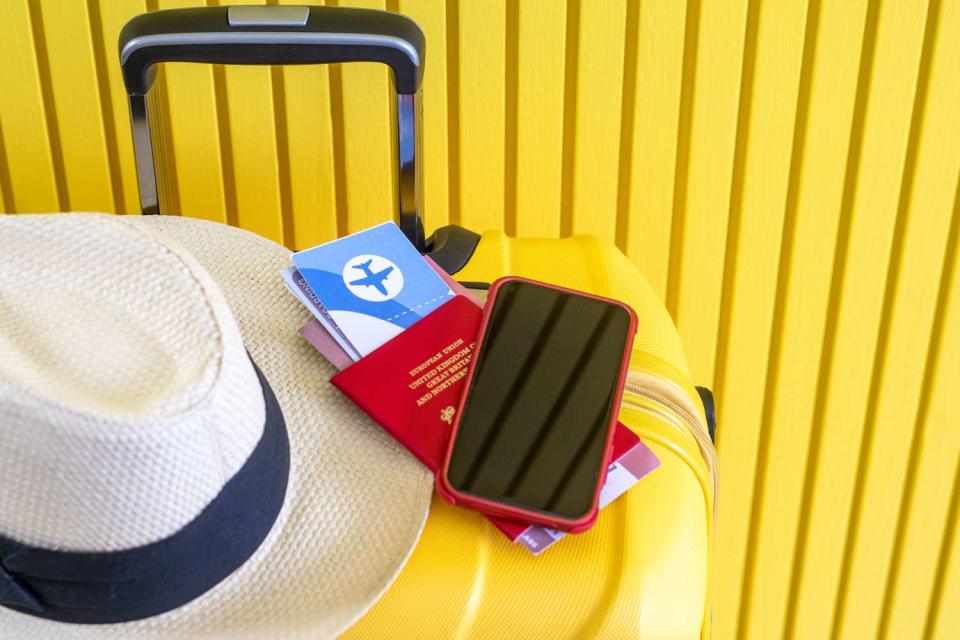 <p>Getty</p> Stock image of passport, ticket, phone and hat on luggage