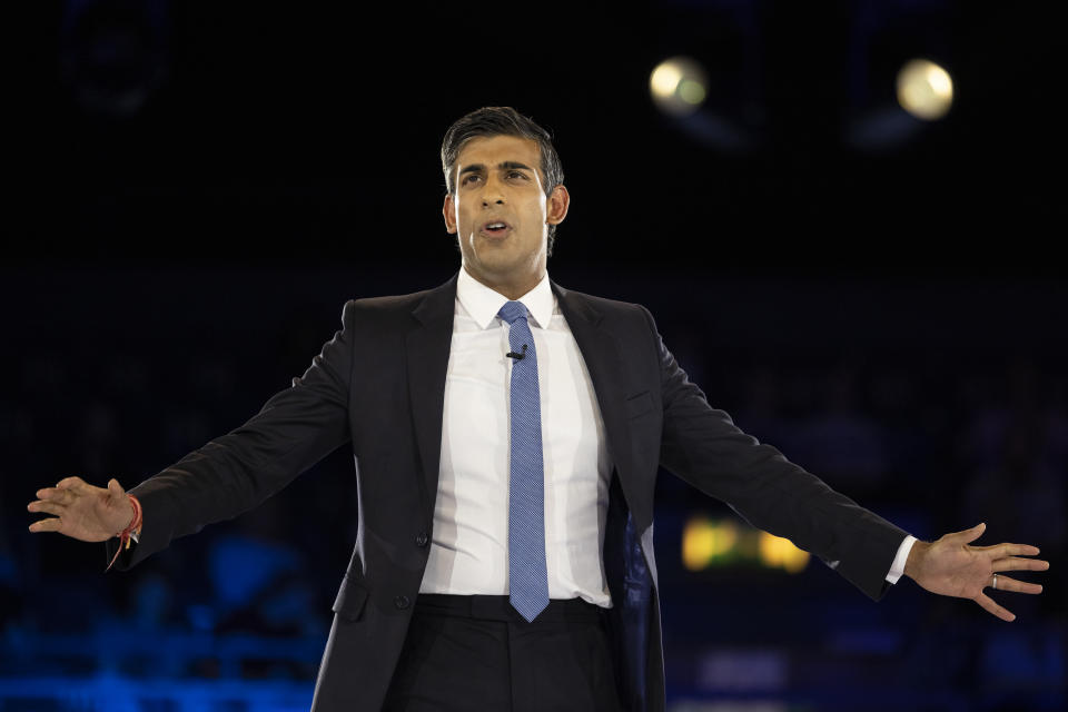 Rishi Sunak  arms wide apart, delivers a speech.