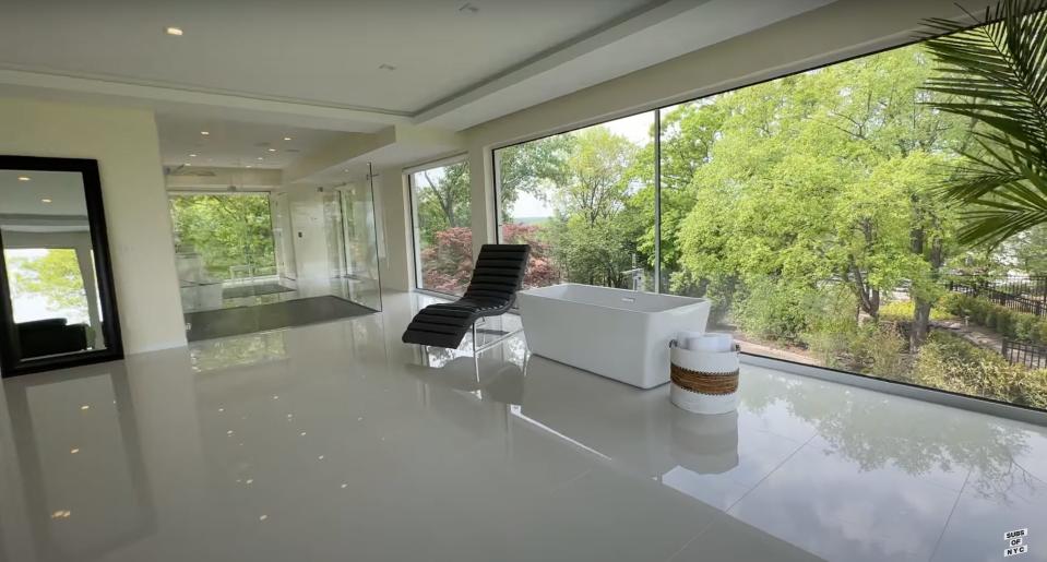 A bathtub next to windows overlooking foliage.