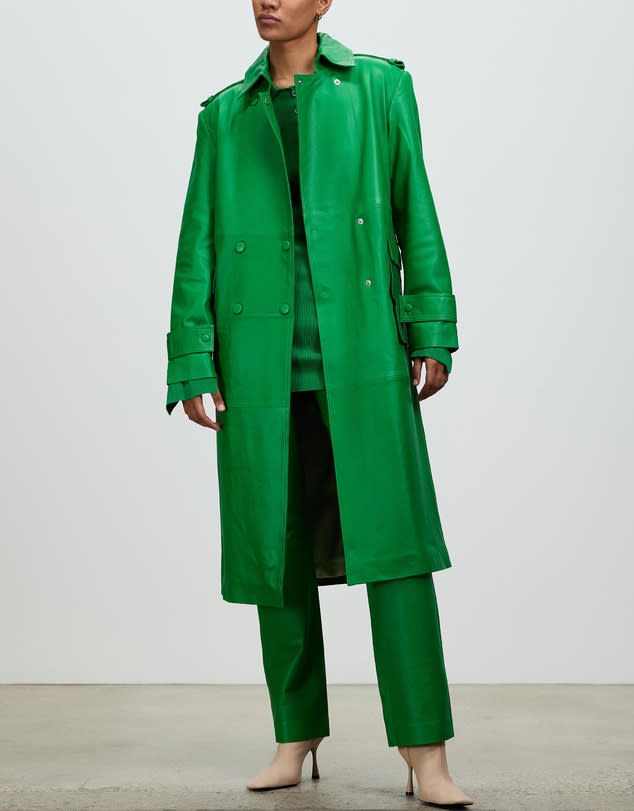 Model wears knee-length bright green Remain Birger Christensen Leather Pirene Coat with matching pants and beige stilettos. 