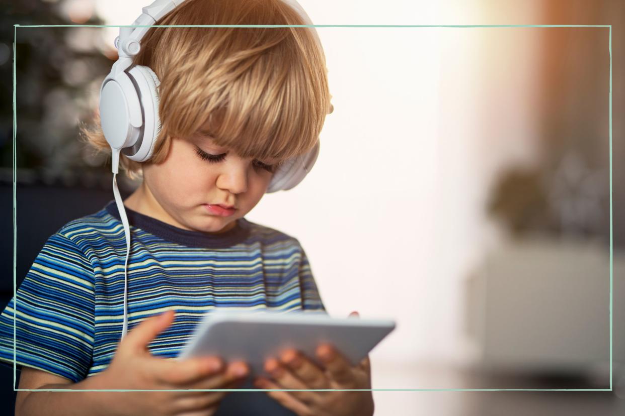  A toddler watching a video on a tablet with headphones on. 