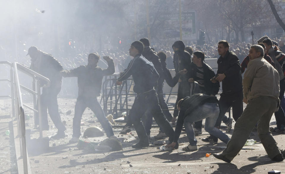 FILE - In this Friday Feb. 7, 2014 file photo, Bosnian protesters throw stones towards a local government building during a protest in the Tuzla, Bosnia. The violence engulfing Bosnia in recent days, with scenes of burning government buildings and protesters pelting police with stones, has many root causes. One of them is the failed privatizations of state-owned companies. (AP Photo/Amel Emric, File)