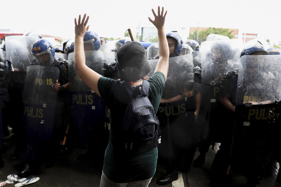 An activist raises her hands as police disperse their group during a rally against presidential frontrunner Ferdinand "Bongbong" Marcos and running mate Sara Duterte, daughter of the current president, during a rally at the Commission on Human Rights in Quezon City, Metro Manila, Philippines on Wednesday. May 25, 2022. Marcos Jr. continues to lead in the official canvassing of votes. (AP Photo/Basilio Sepe)