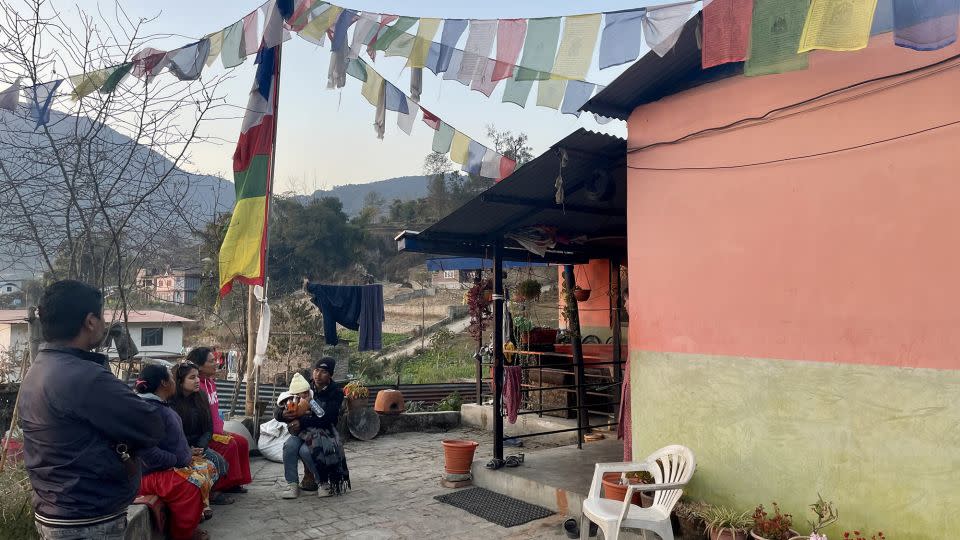 Relatives of Buddhi Maya Tamang, second from left, sit with her outside her house. Her husband, Shukra Tamang, signed up to fight with Russia's forces and is feared dead. - CNN