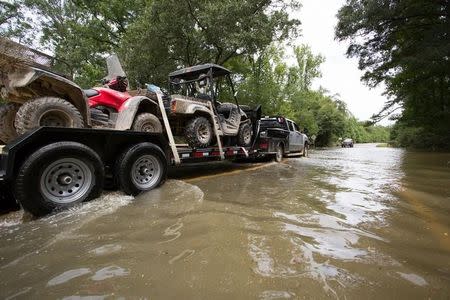 A truck pulling ATVs drives through the remaining floodwaters on Liberty Road in Greenwell Springs, Louisiana, U.S., August 14, 2016. REUTERS/Jeffrey Dubinsky