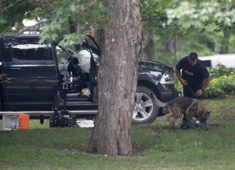 An RCMP officer works with a police dog as they move through the contents of a pickup truck on the grounds of Rideau Hall in Ottawa in July 2020 after a man threatened Prime Minister Justin Trudeau. THE CANADIAN PRESS/Adrian Wyld