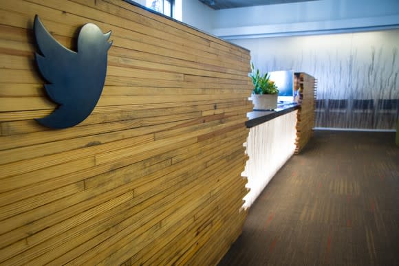 A reception desk surrounded by wood paneling with a Twitter bird emblazoned on the left side.