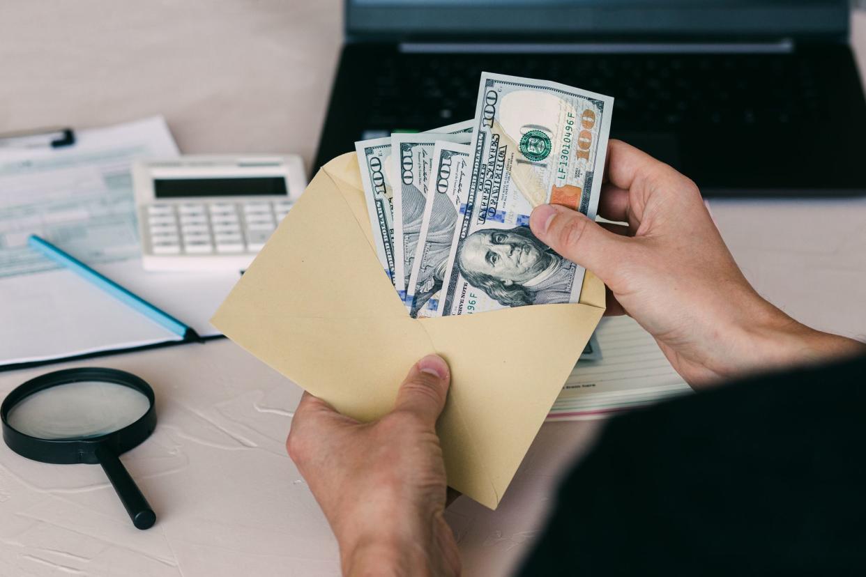 A man's hand holds an envelope with money, counting money American dollars. Income, analyzing business finances, property tax concept.