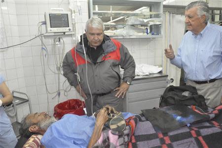 Uruguayan man Raul Fernando Gomez Circunegui (bottom), 58, is visited in a hospital by San Juan Governor Jose Luis Gioja (R), after Circunegui was rescued after disappearing four months ago in the remote Andes Mountains, in San Juan in this September 8, 2013 handout picture provided by the Government of San Juan Province. REUTERS/Government of San Juan Province/Handout via Reuters