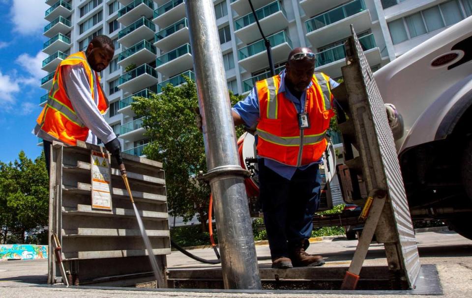 Stormwater Operator A, Keiyatta Gardner, 49, right, and Stormwater Operator B, Jelanie Rouland, 30, vacuum clean the trash rack near 10th Street and West Avenue in Miami Beach, Florida, on Wednesday, May 25, 2022. The trash rack is the first station to intercept trash and debris for treatment of stormwater runoff before ultimately being dissipated into the bay.