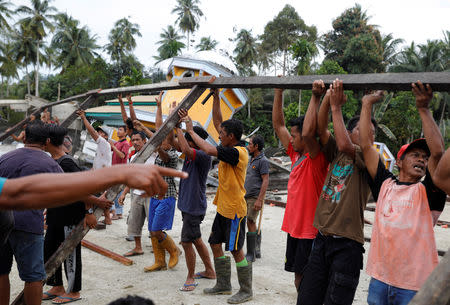 Villagers hold a wooden beam as they build a temporary mosque at the epicentre of a devastating earthquake at Lende Tovea village in Donggala, Indonesia Sulawesi island, October 6, 2018. REUTERS/Beawiharta