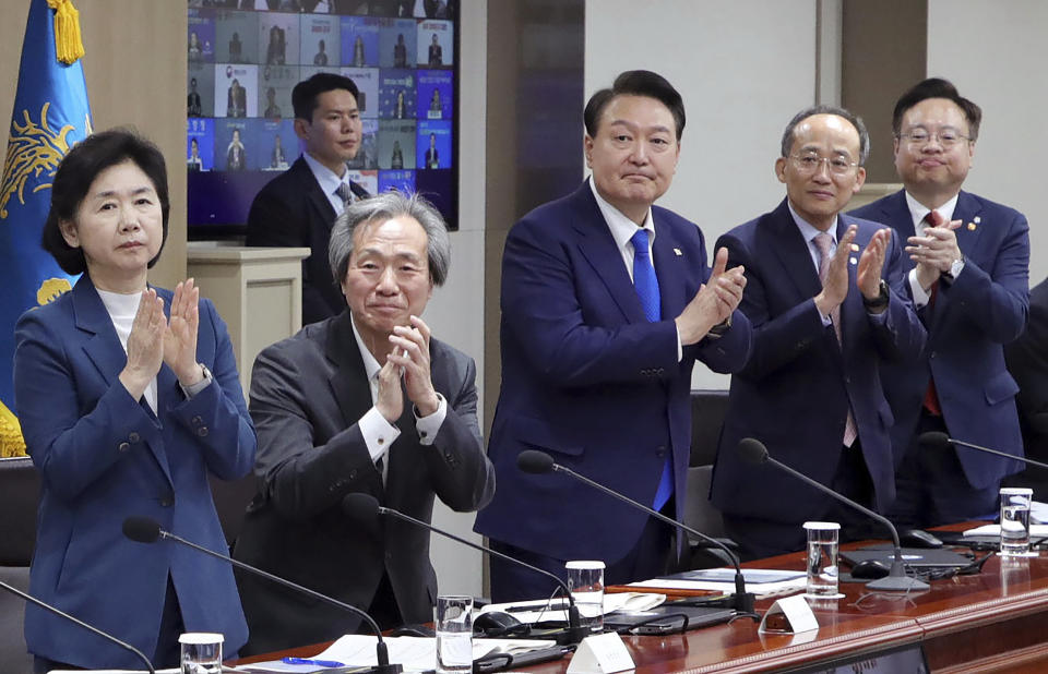 South Korean President Yoon Suk Yeol, center, applauds to encourage medical workers during a meeting of the Central Disaster and Safety Countermeasures Headquarters about measures to deal with the coronavirus pandemic at the presidential office in Seoul, South Korea, Thursday, May 11, 2023. South Korea will drop its COVID-19 quarantine requirements and end testing recommendations for international arrivals starting next month after the World Health Organization declared the end of the global health emergency. (Yonhap via AP)