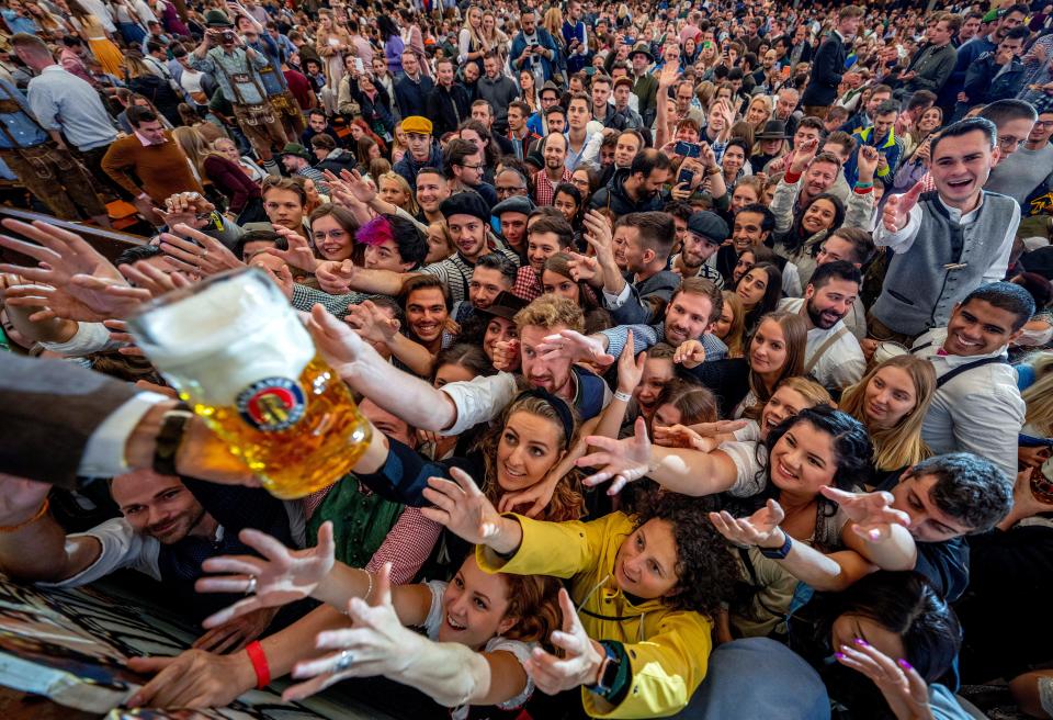 September 17, 2022: Young people reach out for free beer in one of the beer tents on the opening day of the 187th Oktoberfest beer festival in Munich, Germany. Oktoberfest is back in Germany after two years of pandemic cancellations.