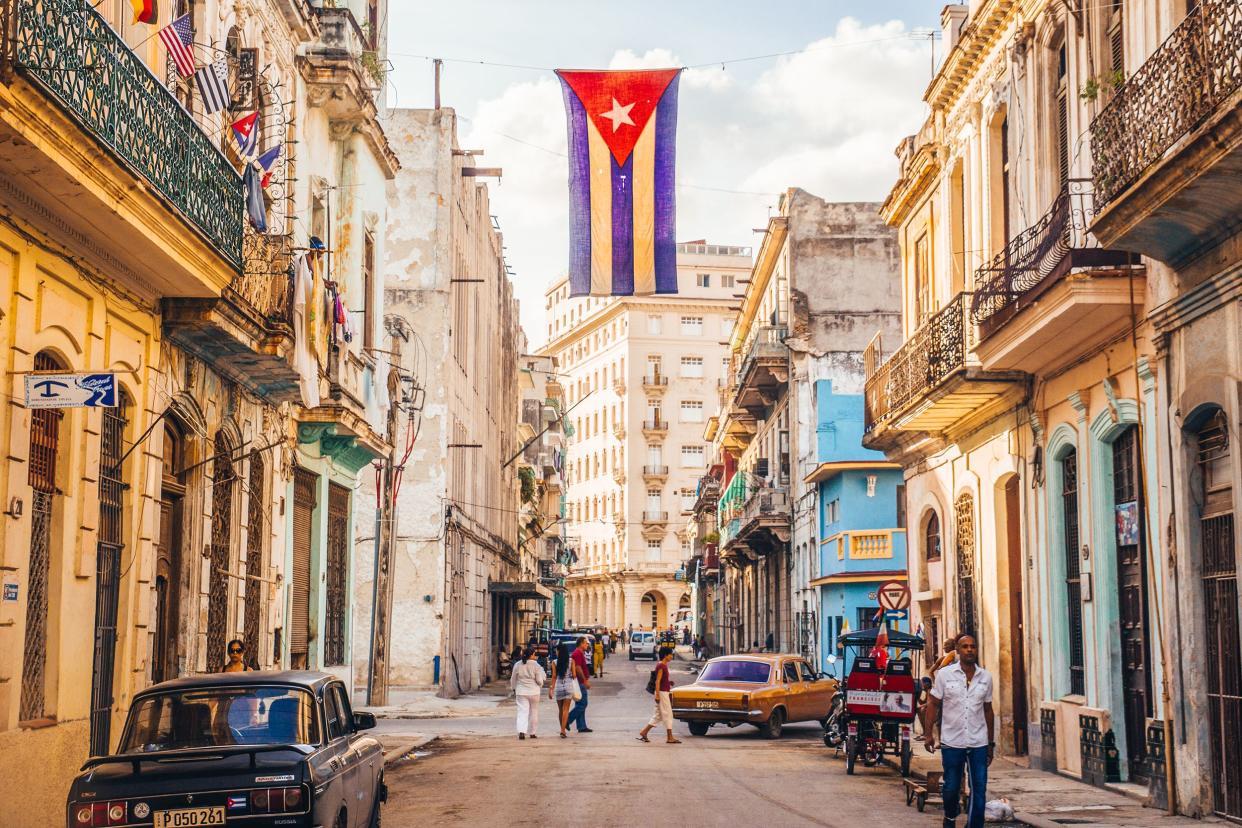 Cuban flag with holes waves over a street in Central Havana