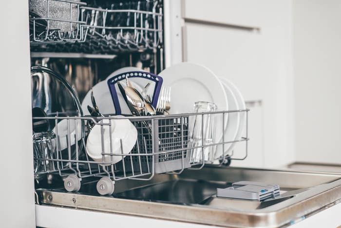 Open dishwasher filled with clean dishes and utensils