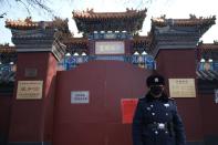 A police officer stands guard in front of the closed gate of Lama Temple where a notice saying that the temple is closed for the safety concern following the outbreak of a new coronavirus is seen, in Beijing