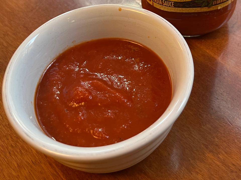 Classico marinara sauce in a white bowl with Classico jar next to it on wooden table