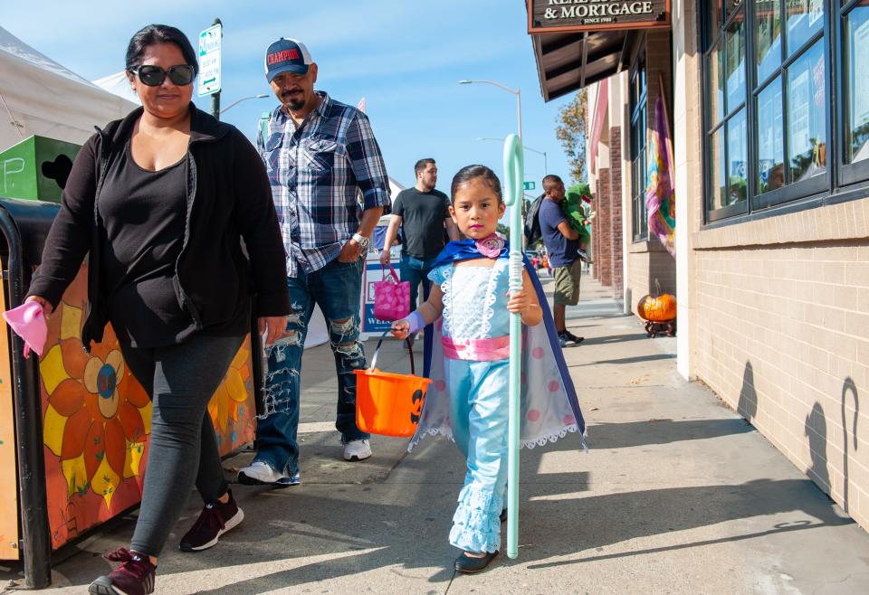 A young girl wearing a Bo-Peep costume from "Toy Story 4" walks with her family during the 2019 downtown Trick-or-Treat event in Salinas, Calif, on Saturday, Oct. 26, 2019.