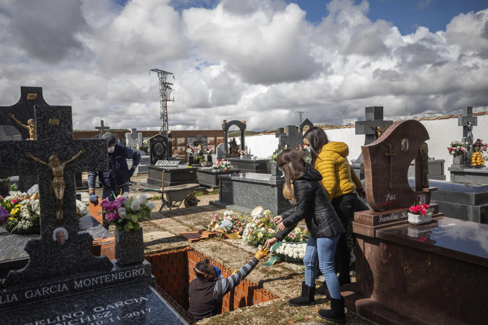 Family members, right, attend the burial of Rosalia Mascaraque, 86, during the coronavirus outbreak in Zarza de Tajo, central Spain, Wednesday, April 1, 2020. The new coronavirus causes mild or moderate symptoms for most people, but for some, especially older adults and people with existing health problems, it can cause more severe illness or death. (AP Photo/Bernat Armangue)