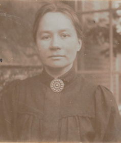 Sepia photograph of Jo van Gogh-Bonger. She wears a round pendant at her neck and her hair is tied back.