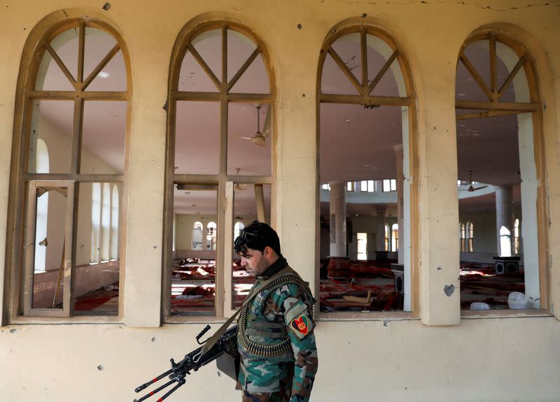 An Afghan security force member inspects a damaged mosque at the site of an attack in a U.S. military air base in Bagram