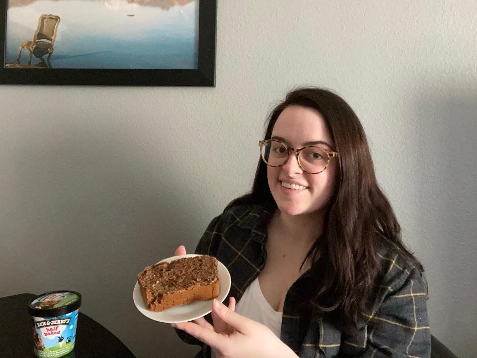 the writer wearing a flannel and holding a piece of plated ice cream bread while sitting at a table