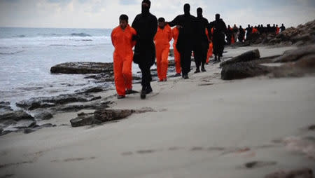 Men in orange jumpsuits purported to be Egyptian Christians held captive by the Islamic State (IS) are marched by armed men along a beach said to be near Tripoli, in this still image from an undated video made available on social media on February 15, 2015. REUTERS/Social media via Reuters TV