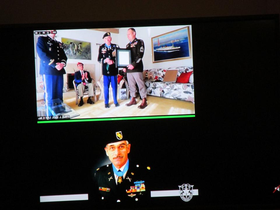 Maj. John Duffy, center, is inducted as a distinguished member of the Special Forces regiment during a ceremony held Thursday, April 20, 2023, at Fort Bragg. Duffy is seen via video call from his home.