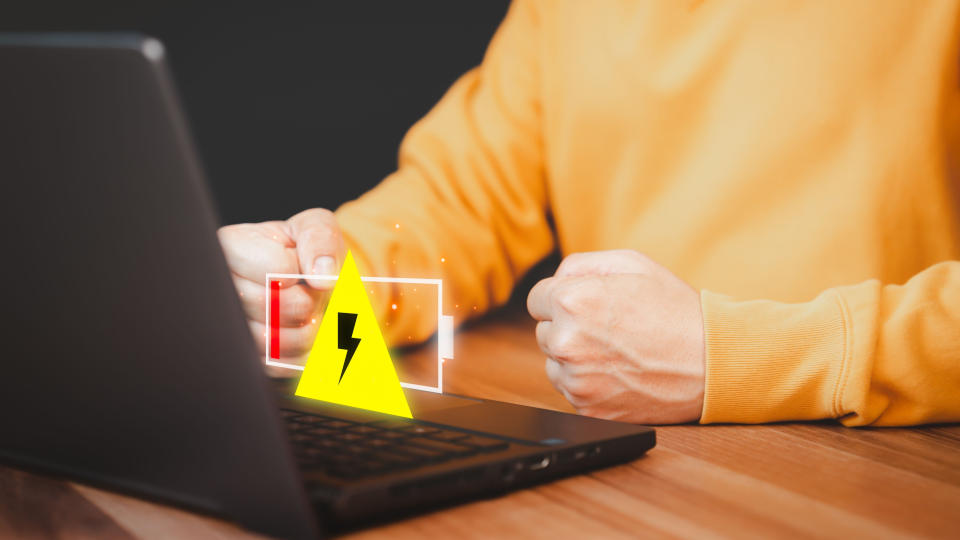 a young person with a fist next to a laptop with low power