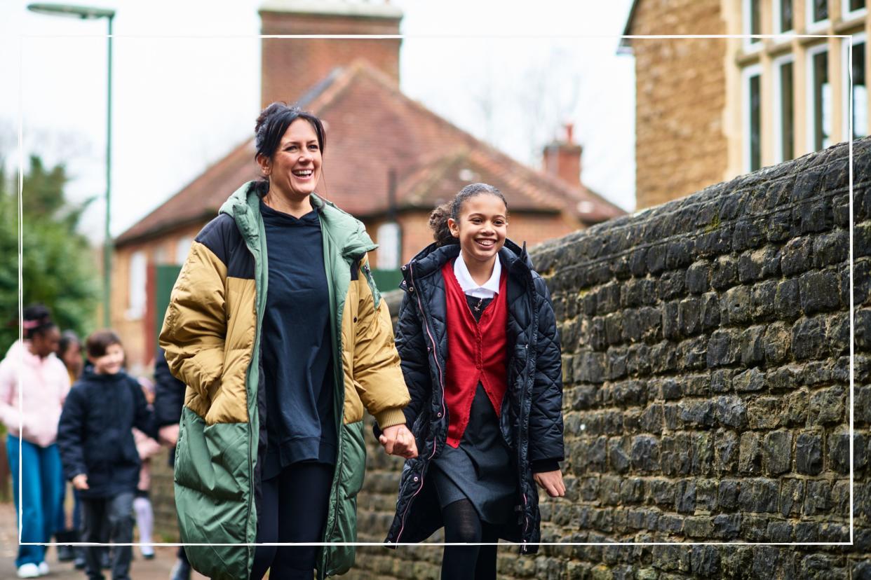  Smiling mother walking her daughter to school. 