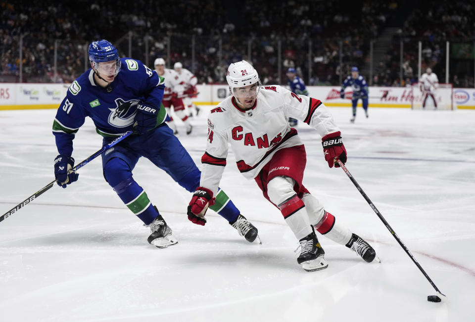 Carolina Hurricanes' Seth Jarvis (24) skates with the puck past Vancouver Canucks' Tyler Myers (57) during the second period of an NHL hockey game in Vancouver, British Columbia, on Monday, Oct. 24, 2022. (Darryl Dyck/The Canadian Press via AP)