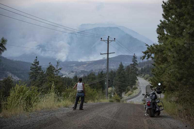 Alfred Higginbottom, of the Skuppah Indian Band – a Nlaka'pamux First Nations government, watches as a wildfire burns on the side of a mountain in Lytton, British Columbia.