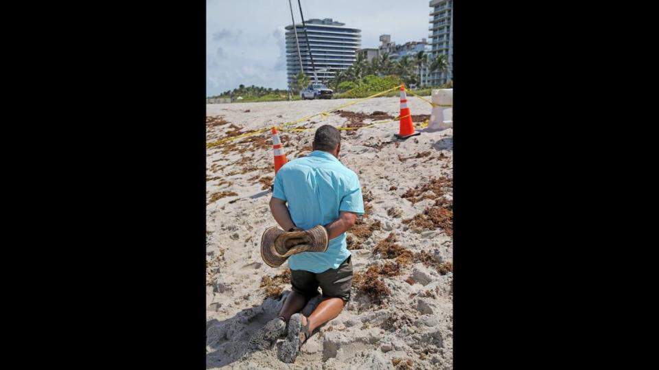 A man prays at the site of the Champlain Towers South condo building collapse in Surfside, Florida, June 25, 2021. The building collapsed early Thursday morning.