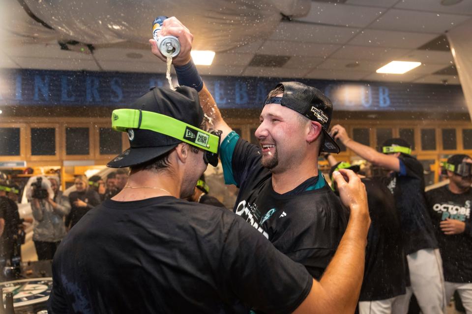 Seattle Mariners' Cal Raleigh, right, celebrates in the clubhouse after the team's baseball game against the Oakland Athletics, Friday, Sept. 30, 2022, in Seattle. The Mariners won 2-1 on a homer by Raleigh to clinch a spot in the playoffs. (AP Photo/Stephen Brashear)