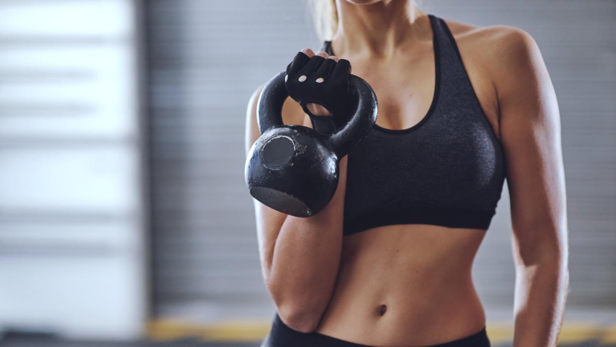  a photo of a woman with abs holding a kettlebell 