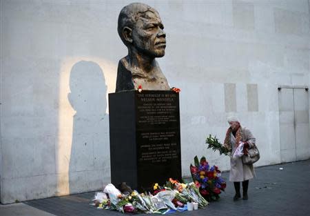 A woman leaves flowers at a statue of South Africa's former president Nelson Mandela at South Bank in London December 6, 2013. REUTERS/Suzanne Plunkett