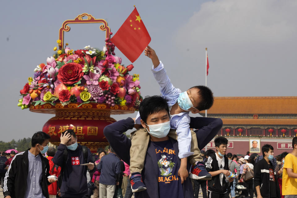 Tourists wearing masks to protect from the coronavirus stand near a floral decoration set up for the National Day celebrations on Tiananmen Square in Beijing on Thursday, Oct. 1, 2020. Negative perceptions of China have increased sharply in many of the world's advanced economies, especially in Australia and the U.K., a new survey from the Pew Research Center showed Tuesday, Oct. 6, 2020. (AP Photo/Ng Han Guan)