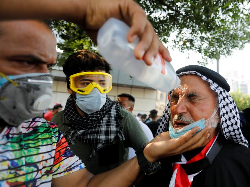 Demonstrators spray medical fluid on the face of a man who was affected by tear gas during a protest over corruption, lack of jobs, and poor services, in Baghdad