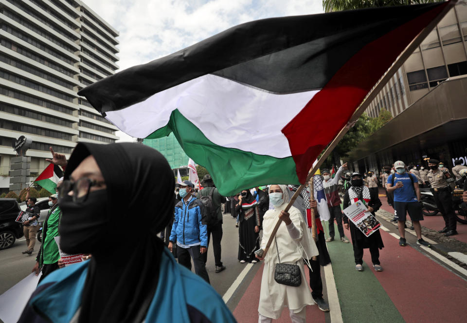 A Muslim woman waves a Palestinian flag during a rally condemning Israeli attacks on the Palestinians in Jakarta, Indonesia, Tuesday, May 18, 2021. (AP Photo/Dita Alangkara)