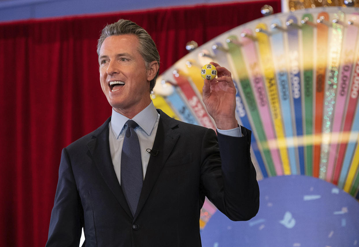 FILE - In this June 4, 2021, file photo, California Gov. Gavin Newsom holds up a lottery ball at the California Lottery Headquarters on Friday, June 4, 2021, in Sacramento, Calif., while drawing numbers for California's new vaccine incentive program. California, the first state in America to put in place a coronavirus lockdown, is now turning a page on the pandemic. Most of California's coronavirus restrictions will disappear Tuesday, June 15, 2021. (Paul Kitagaki Jr./The Sacramento Bee via AP, File)/The Sacramento Bee via AP)