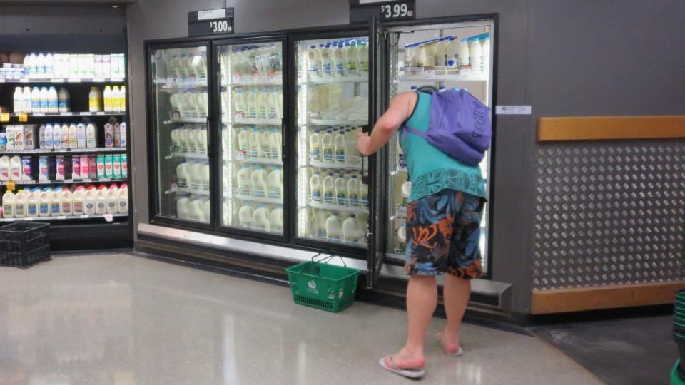 man getting milk out of fridge at supermarket