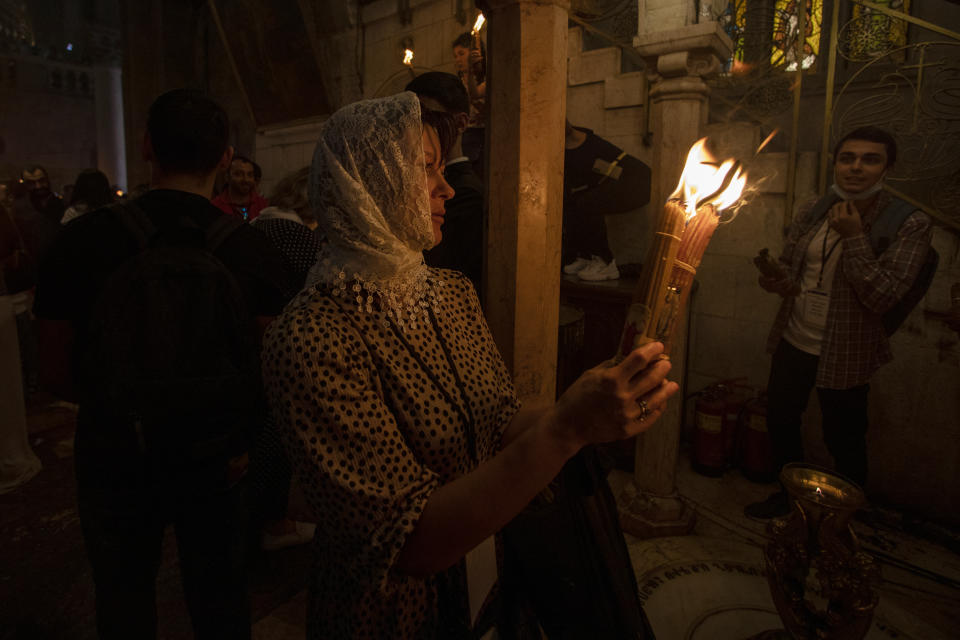 A Christian pilgrim holds candles during the ceremony of the Holy Fire at Church of the Holy Sepulchre, where many Christians believe Jesus was crucified, buried and rose from the dead, in the Old City of Jerusalem, Saturday, May 1, 2021. Hundreds of Christian worshippers took use of Israel's easing of coronavirus restrictions Saturday and packed a Jerusalem church revered as the site of Jesus' crucifixion and resurrection for an ancient fire ceremony ahead of Orthodox Easter. (AP Photo/Ariel Schalit)