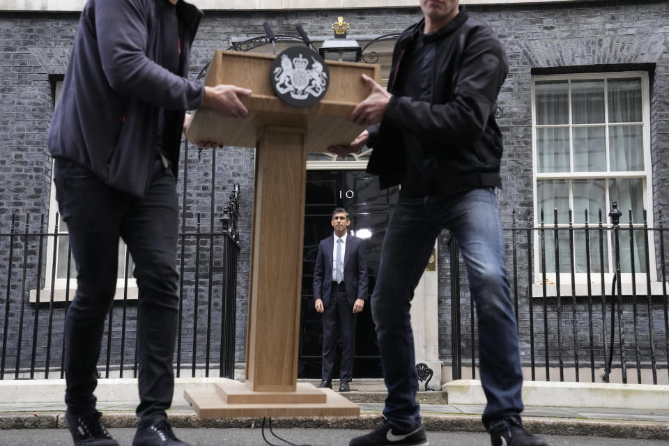 FILE - New British Prime Minister Rishi Sunak, centre, poses for the media as the pulpit is moved after his speech at Downing Street in London, Tuesday, Oct. 25, 2022, after returning from Buckingham Palace where he was formally appointed to the post by Britain's King Charles III. In his first month as Britain's prime minister, Rishi Sunak has stabilized the economy, reassured allies from Washington to Kyiv and even soothed the European Union after years of sparring between Britain and the bloc. But Sunak’s challenges are just beginning. He is facing a stagnating economy, a cost-of-living crisis – and a Conservative Party that is fractious and increasingly unpopular after 12 years in power. (AP Photo/Frank Augstein, File)