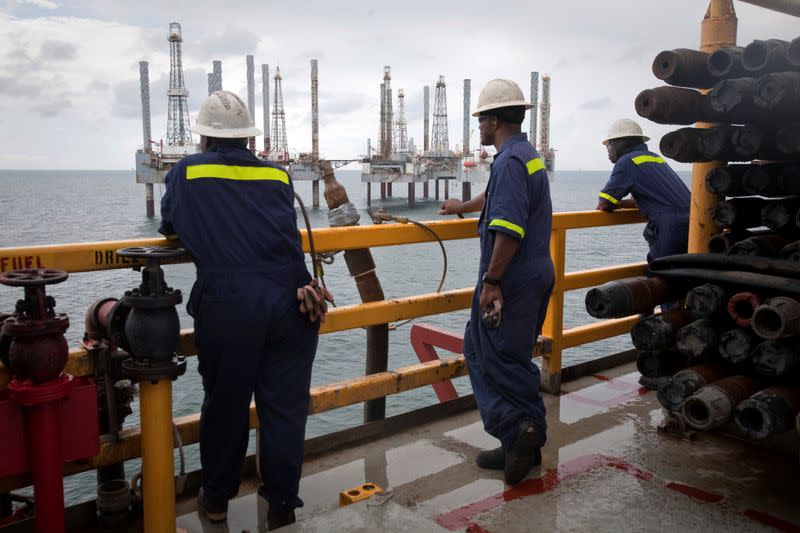 FILE PHOTO: Crew members look over idle oil rigs in the Gulf of Mexico near Port Fourchon, Louisiana